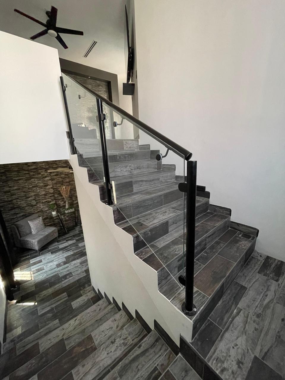 Tempered glass stair railing with black posts and handrail by FerMac