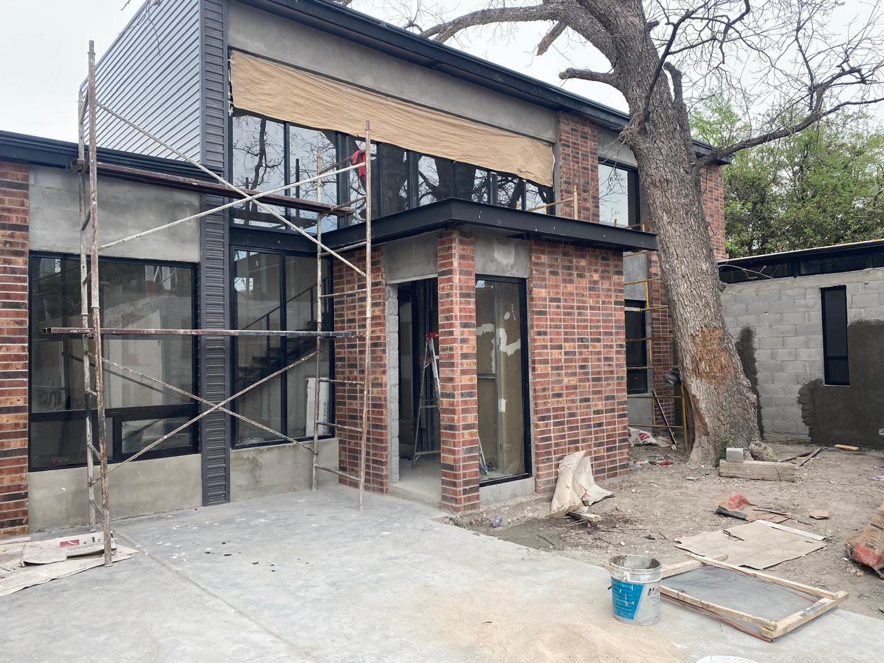 Two-story brick facade with black aluminum window walls by FerMac