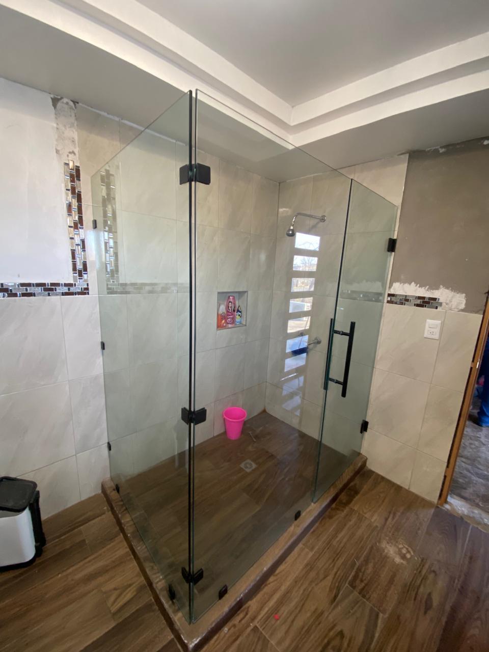Frameless tempered glass shower enclosure with black hardware by FerMac