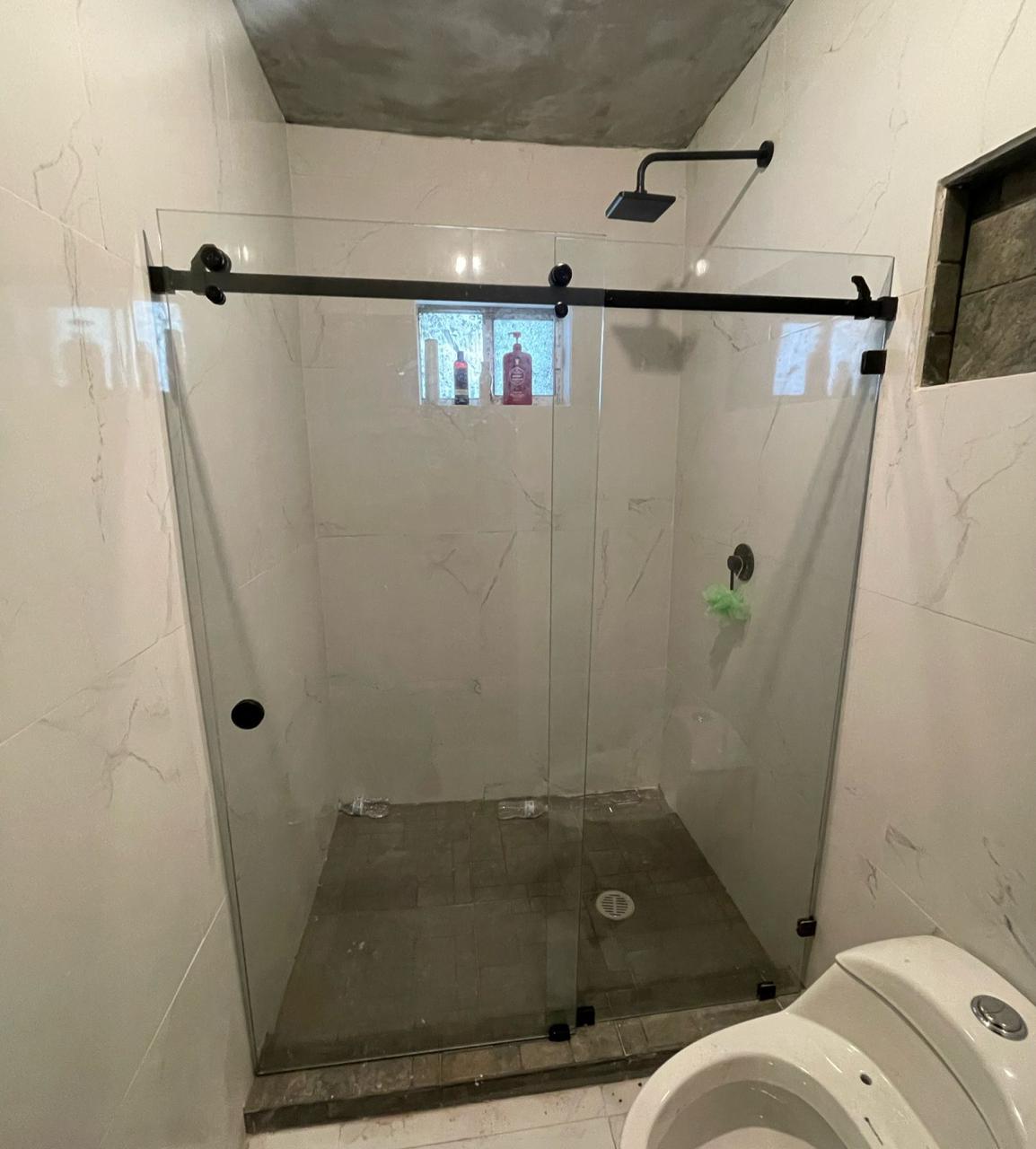 Barn-style sliding glass shower door with black track by FerMac
