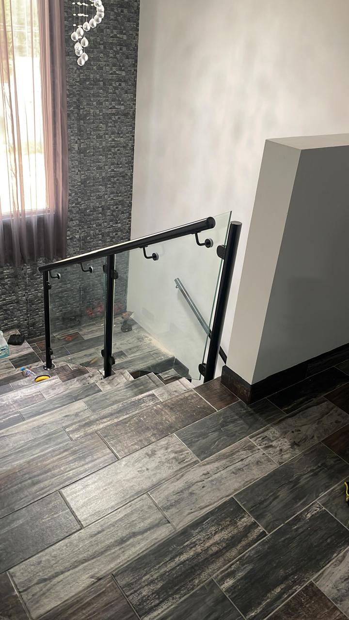 Tempered glass stair railing with black hardware by FerMac