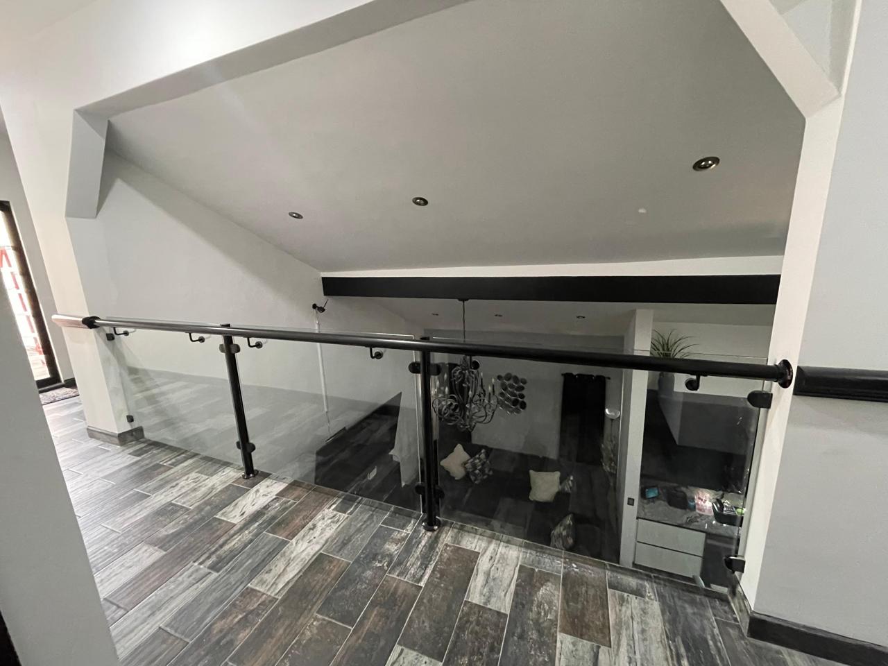 Tempered glass railing with black handrail by FerMac